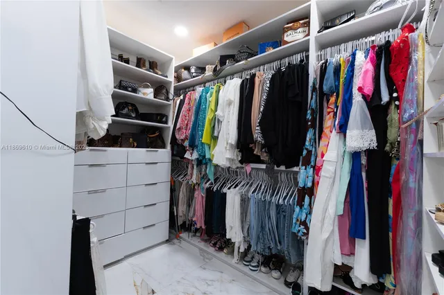 a view of walk in closet with clothes and shoes