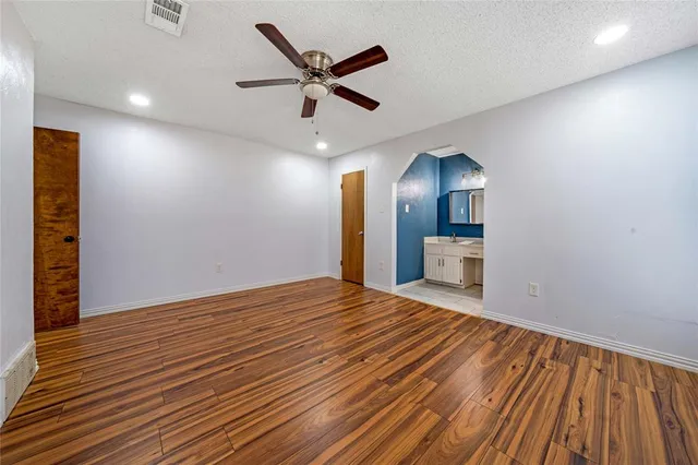 an empty room with wooden floor and a hallway