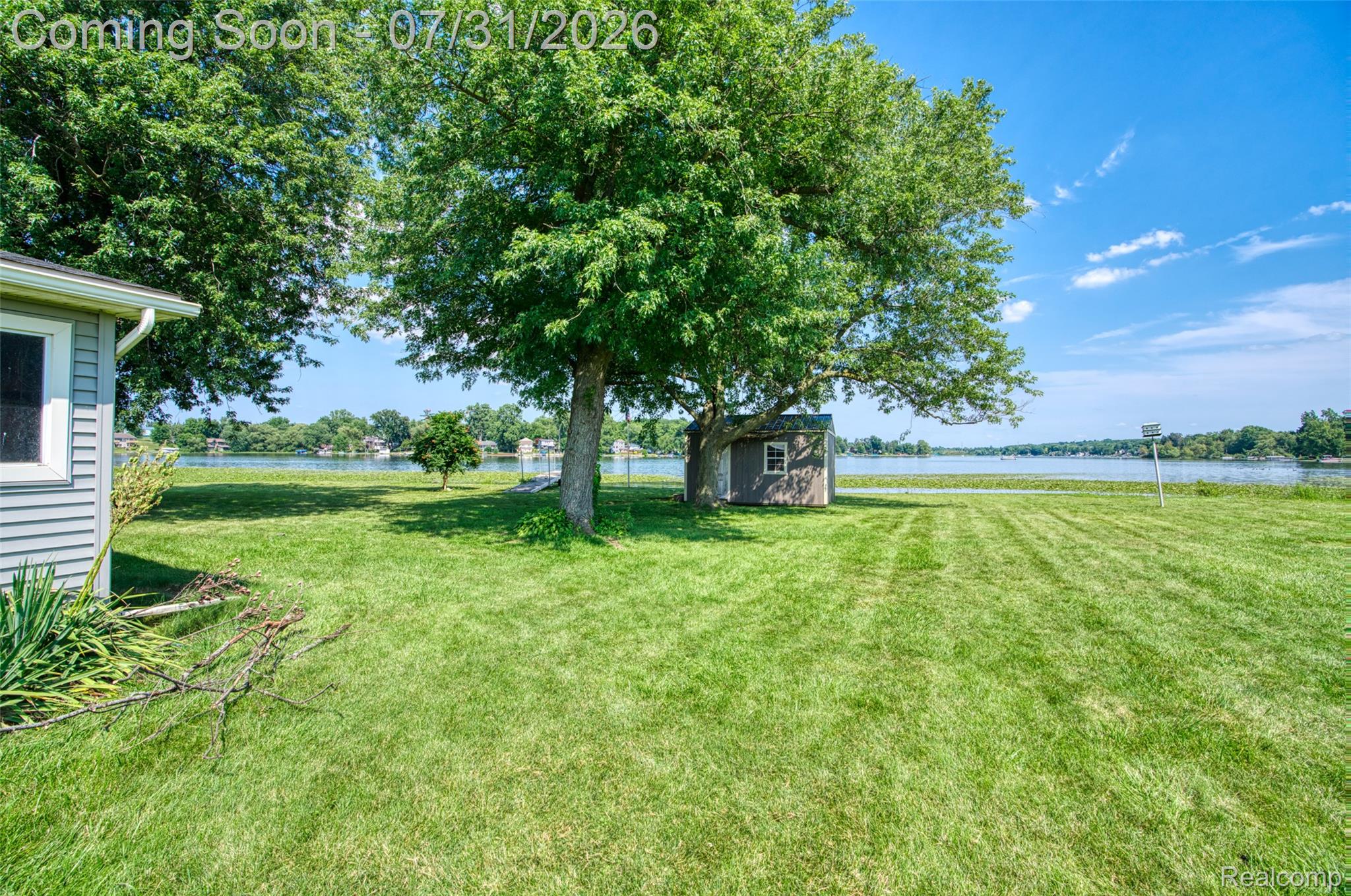 5269 Reno Road Manchester, MI 48158 - Photo 23 of 64 Expansive waterfront property featuring a manicured lawn, mature trees, a detached storage shed, and a broad water body with distant structures