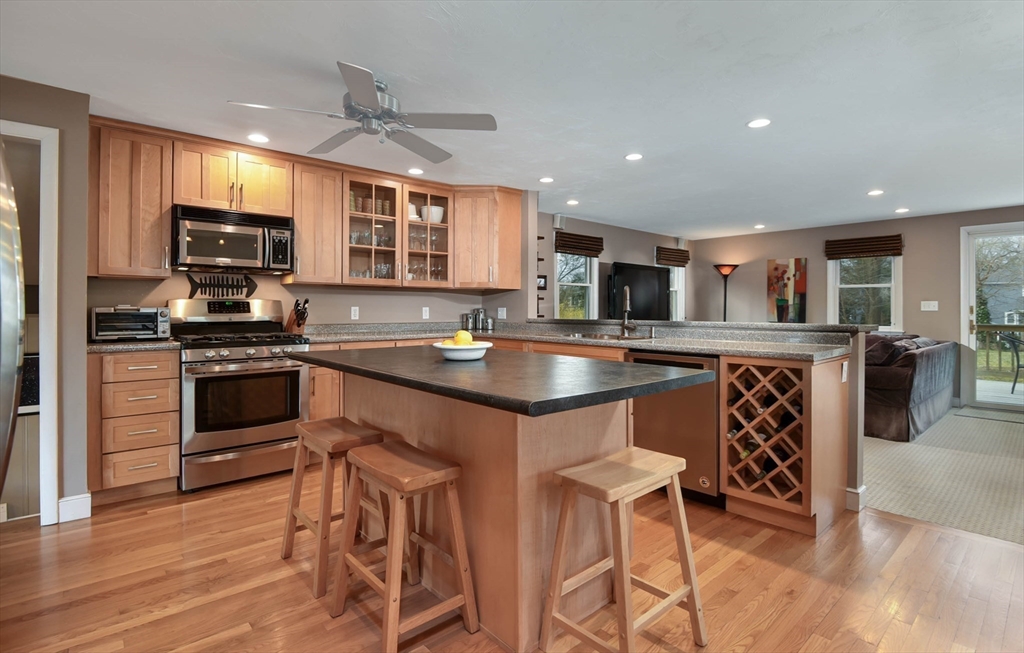 89 Edwardel Road Needham, MA 02492 - Photo 9 of 41 a kitchen with stainless steel appliances granite countertop a stove top oven a sink dishwasher a dining table and chairs with wooden floor