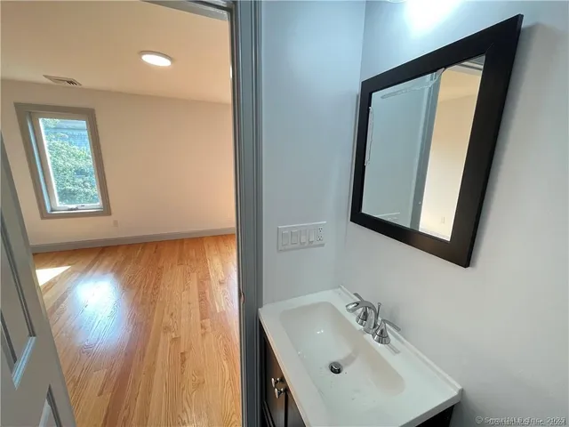 a bathroom with a sink a mirror and wooden floor