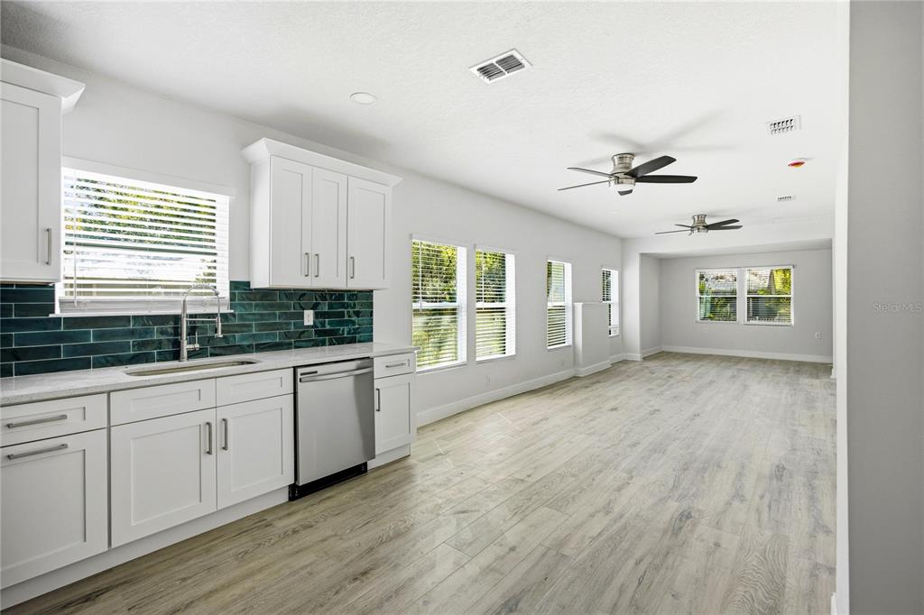 418 Northwest 3rd Avenue Gainesville, FL 32601 - Photo 15 of 31 a open kitchen with granite countertop a stove a sink and white cabinets with wooden floor