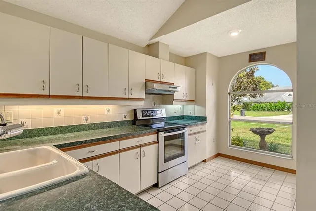 a kitchen with granite countertop a stove sink and cabinets