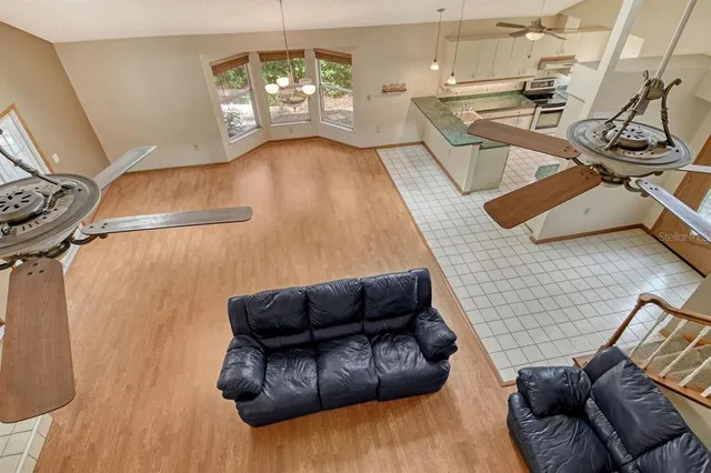 an empty room with wooden floor ceiling fan and windows