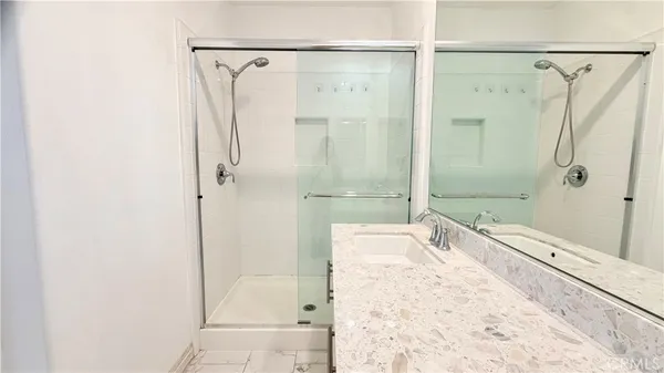 a bathroom with a granite countertop shower a mirror and a sink