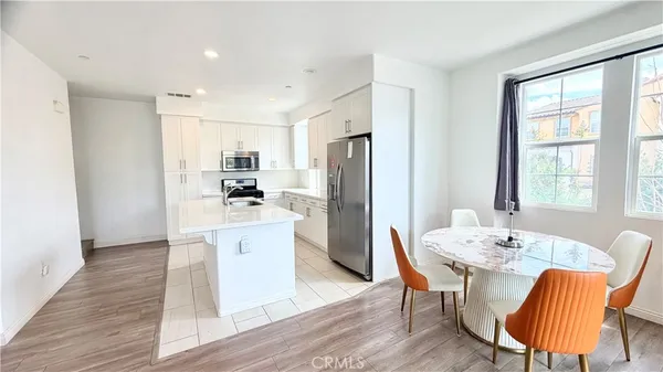a kitchen with stainless steel appliances granite countertop a dining table chairs refrigerator and sink