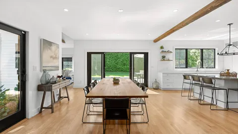 a dining room with wooden floor and large windows