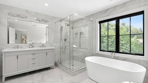 a bathroom with a double vanity sink bathtub and next to a window
