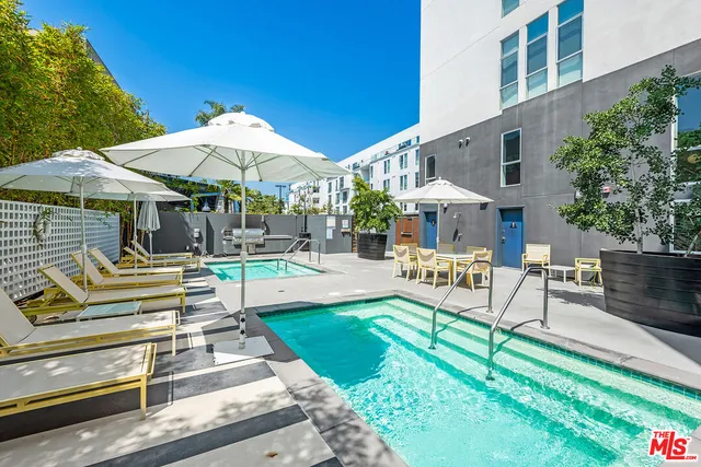 a view of pool with table and chairs under an umbrella