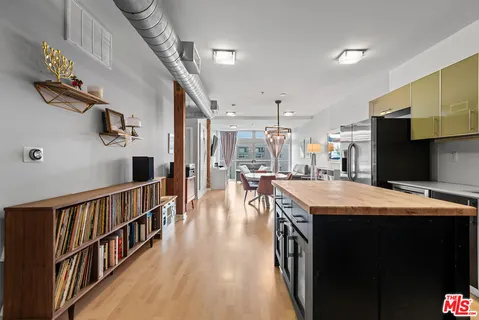 a dining hall with stainless steel appliances granite countertop a refrigerator oven a sink a dining table and chairs with wooden floor