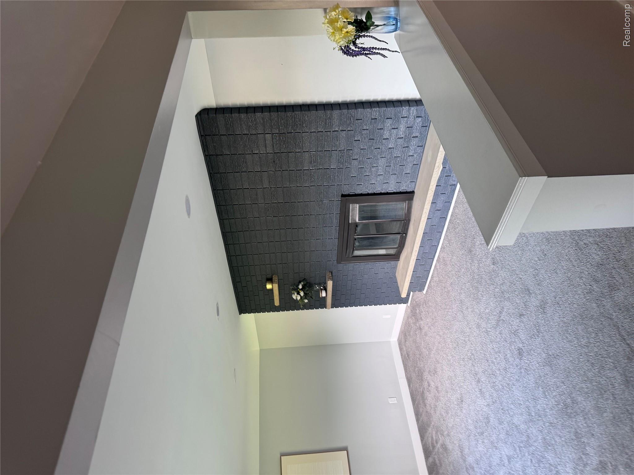 2330 Walton Blvd. Rochester, MI 48309 - Photo 2 of 12 Living area featuring a dark brick fireplace with a light-colored hearth, recessed lighting, wall-mounted floating shelves, and neutral gray carpeting