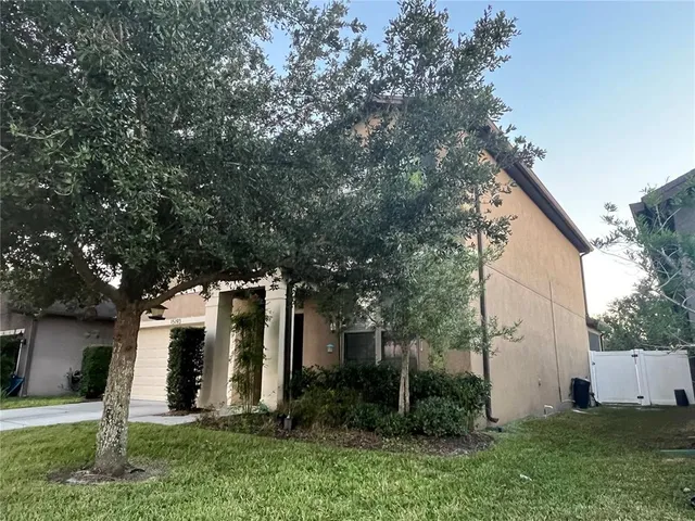 a view of a white house next to a yard with big trees