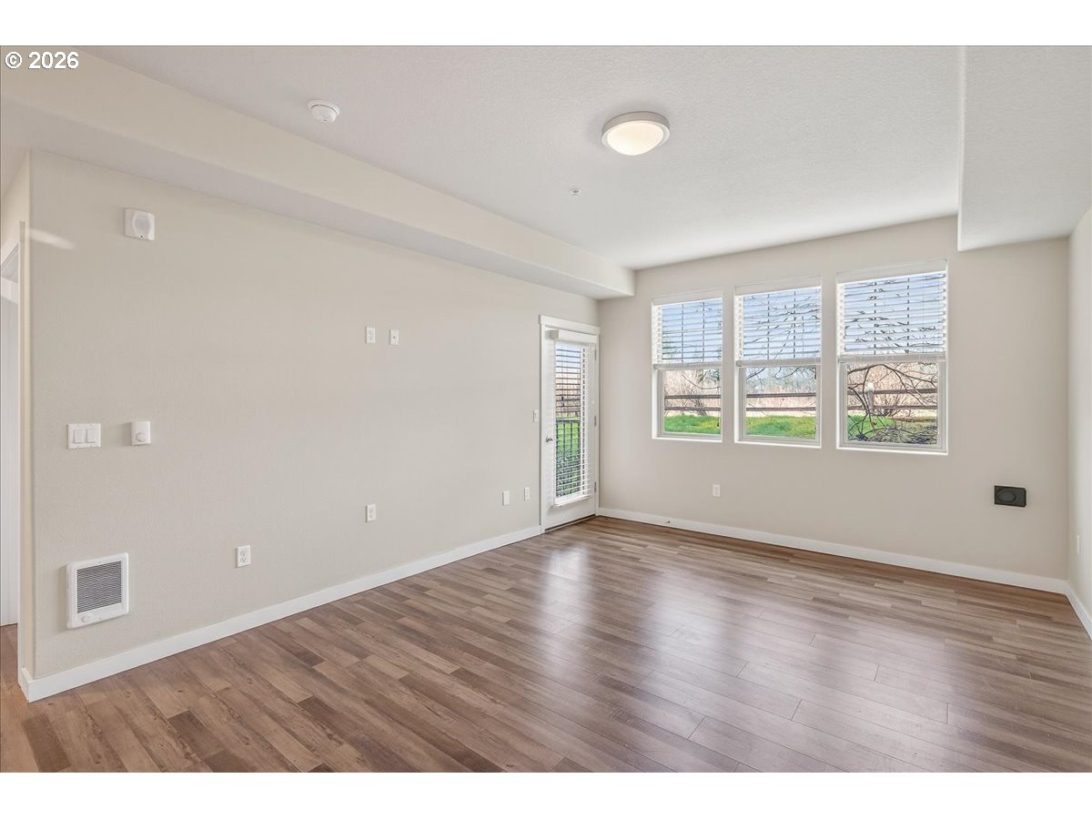 16401 Northwest Chadwick Way, Unit 108 Portland, OR 97229 - Photo 10 of 29 an empty room with wooden floor and windows