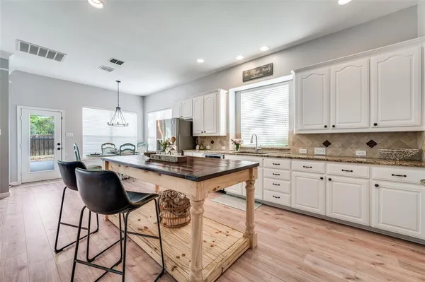 a kitchen with granite countertop white cabinets stainless steel appliances dining table and chairs
