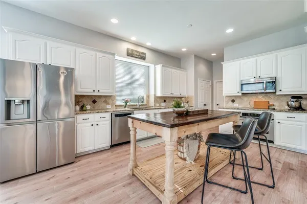 a kitchen with a refrigerator a sink dishwasher a stove and white cabinets with wooden floor