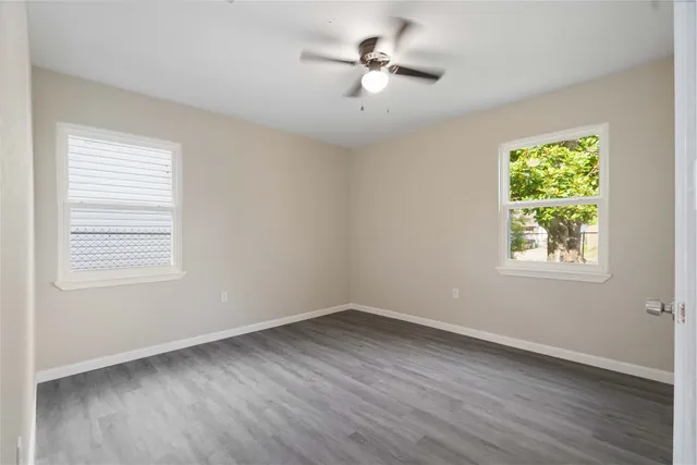 a view of empty room with wooden floor and fan