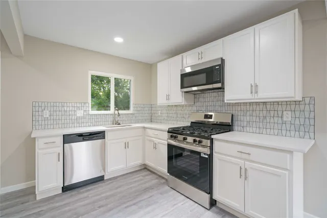 a kitchen with white cabinets stainless steel appliances and sink
