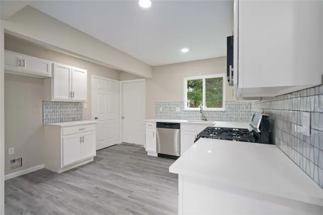 a kitchen with a sink a stove a refrigerator and white cabinets