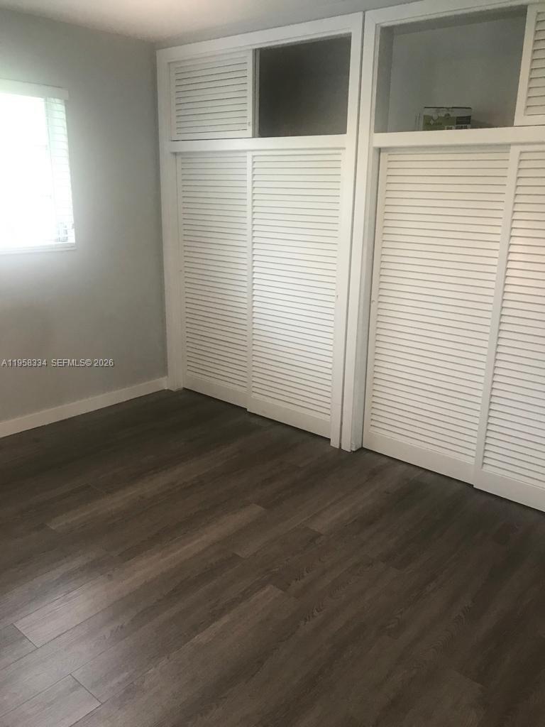 7570 Southwest 82nd Street, Unit F209 Miami, FL 33143 - Photo 11 of 13 an empty room with wooden floor and windows