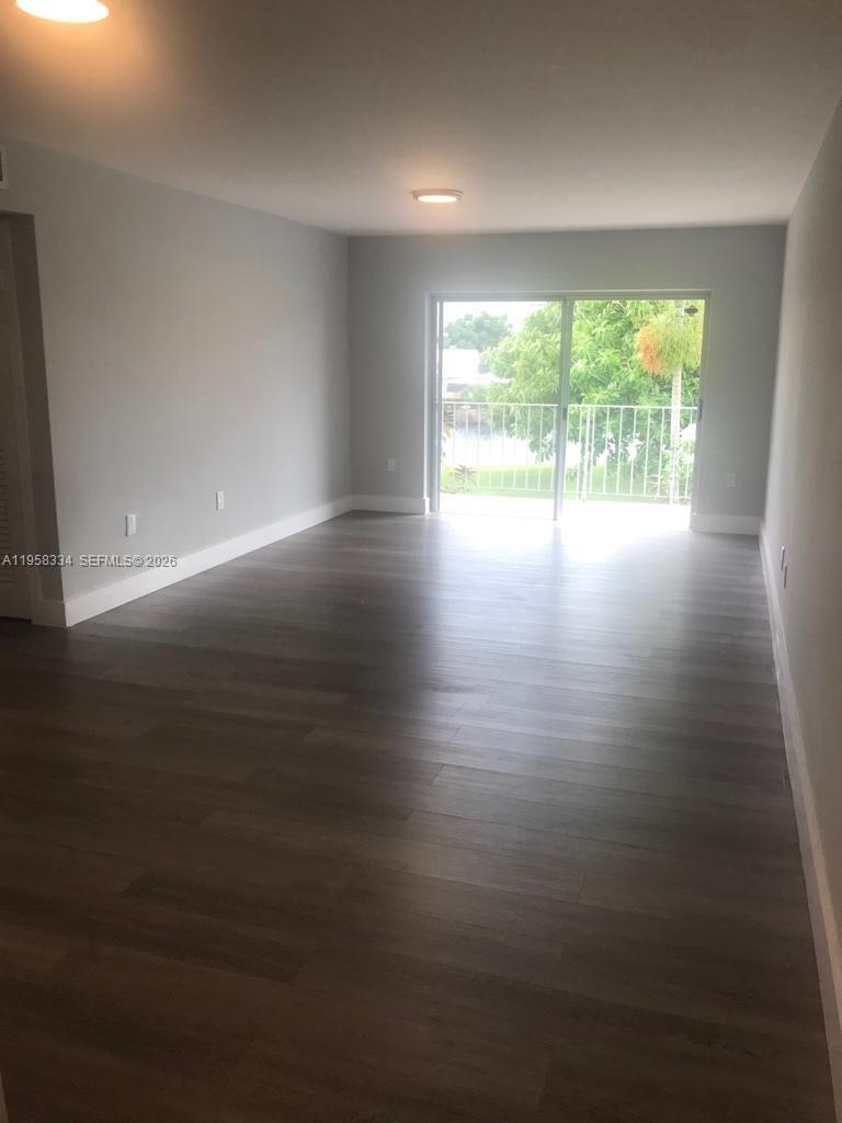 7570 Southwest 82nd Street, Unit F209 Miami, FL 33143 - Photo 3 of 13 wooden floor in an empty room with a window