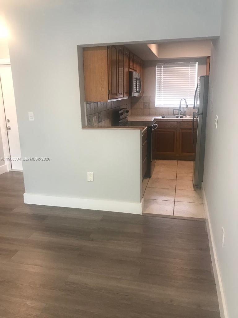 7570 Southwest 82nd Street, Unit F209 Miami, FL 33143 - Photo 4 of 13 a kitchen with granite countertop a stove a sink and a refrigerator