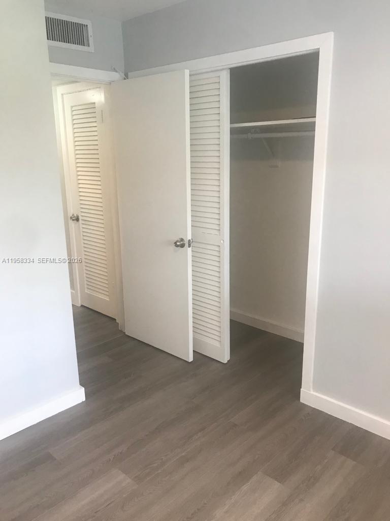 7570 Southwest 82nd Street, Unit F209 Miami, FL 33143 - Photo 5 of 13 an empty room with wooden floor & closet