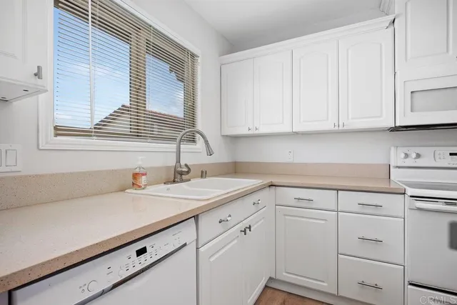 a kitchen with white cabinets and a window