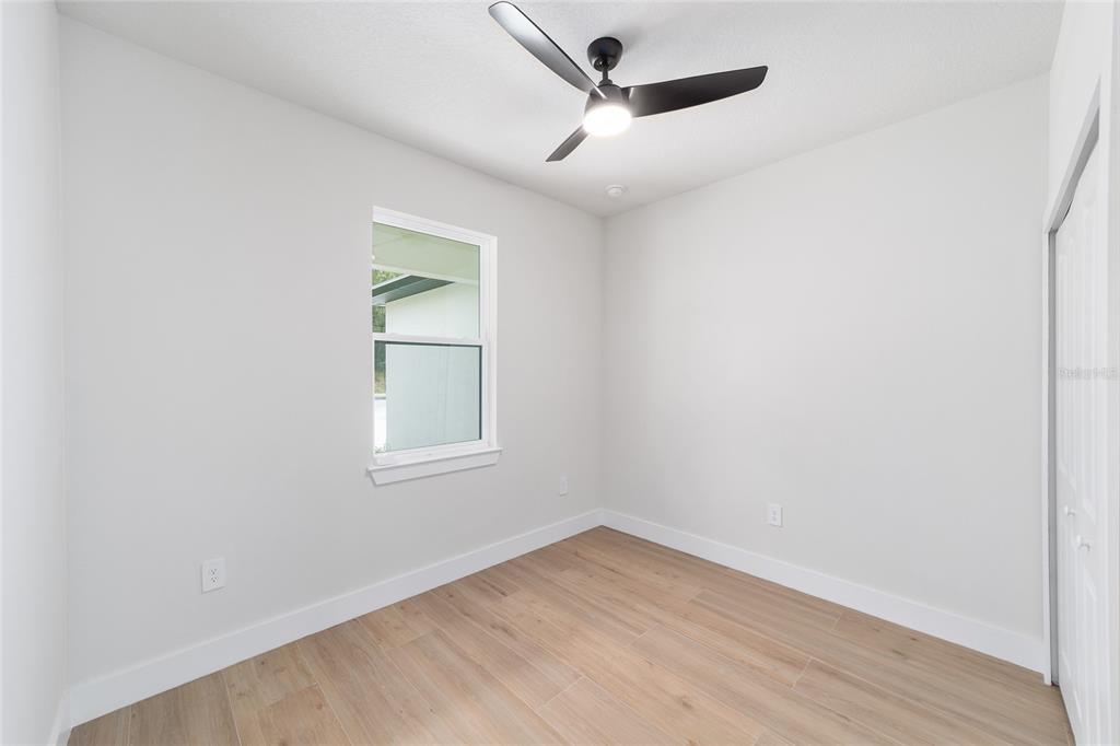 4380 Southwest 159th Court Ocala, FL 34481 - Photo 29 of 52 an empty room with wooden floor ceiling fan and windows