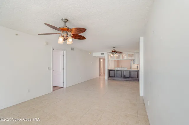 a view of a livingroom with a chandelier fan and kitchen view