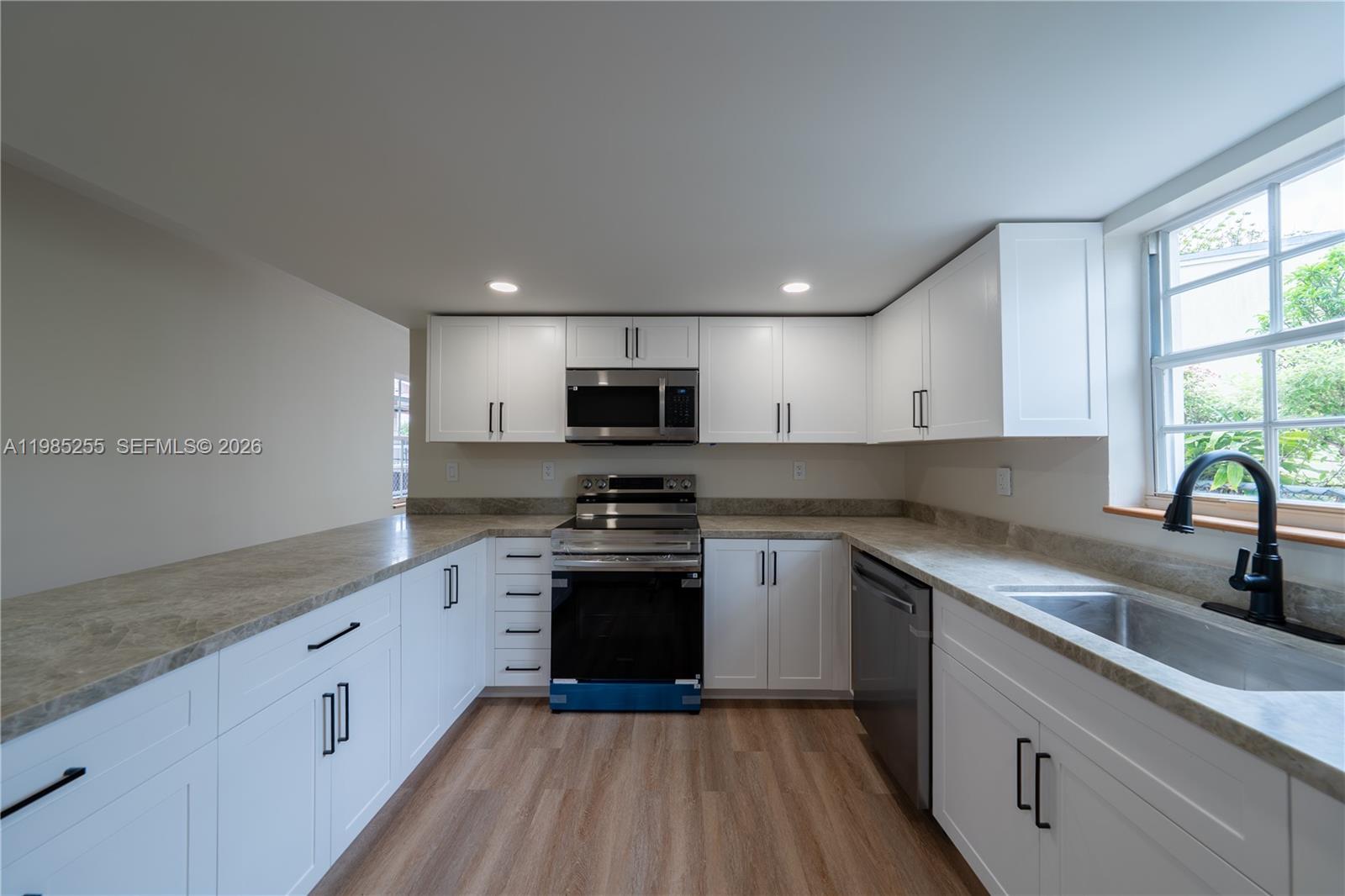 370 Flagami Boulevard Miami, FL 33144 - Photo 2 of 67 a kitchen with stainless steel appliances granite countertop white cabinets a sink dishwasher a stove and a refrigerator with wooden floor