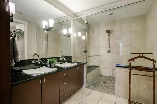 a bathroom with a double vanity sink a toilet a mirror and shower