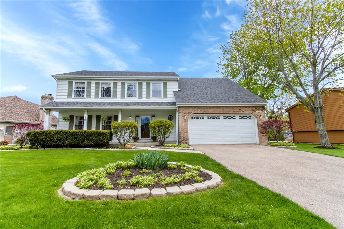 a front view of a house with a garden and trees
