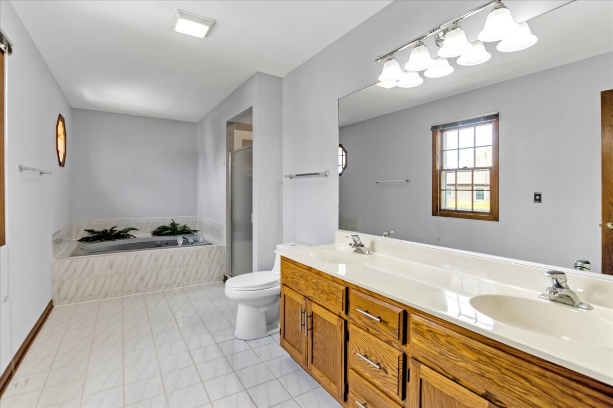 76 Red Fox Run Montgomery, IL 60538 - Photo 17 of 28 a spacious bathroom with a granite countertop double vanity sink a mirror and a bathtub