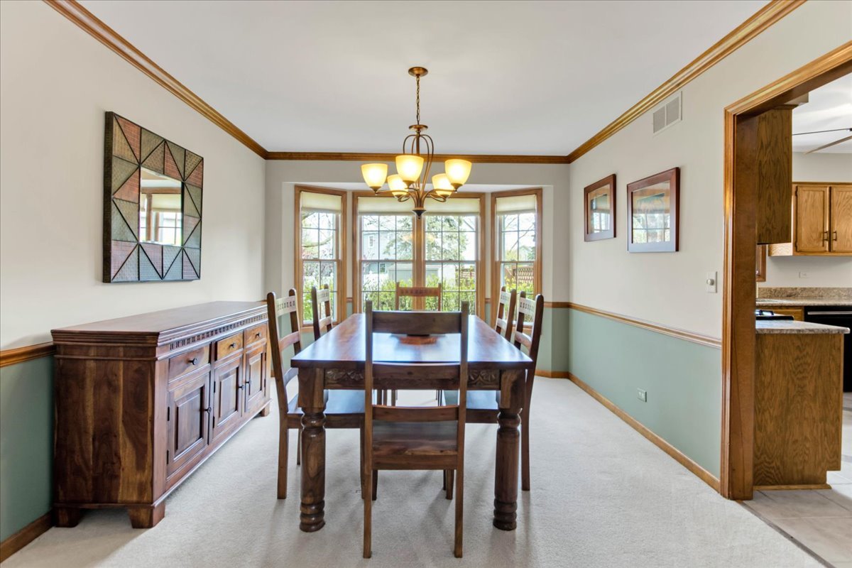 76 Red Fox Run Montgomery, IL 60538 - Photo 7 of 28 a dining room with wooden floor a chandelier a wooden table and chairs