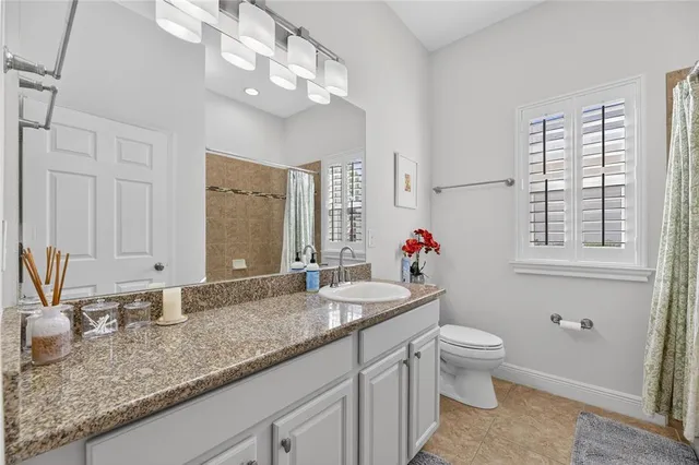 a bathroom with a granite countertop shower a sink and a window