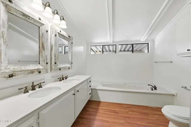 a bathroom with a double vanity sink mirror and bathtub
