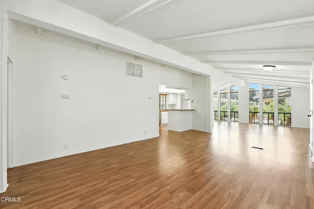 a view of empty room with wooden floor and floor to ceiling window