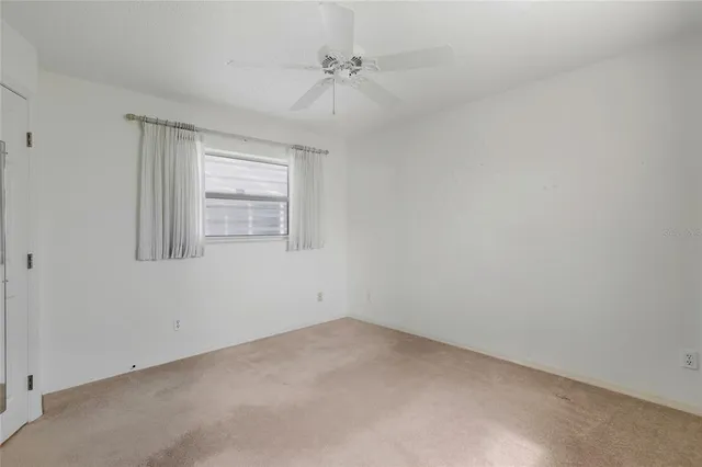 an empty room with a window and a ceiling fan