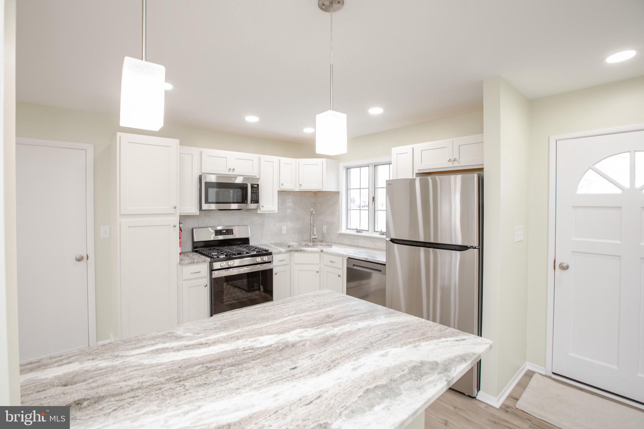 21 Rolling Lane Hamilton, NJ 08690 - Photo 14 of 40 a kitchen with stainless steel appliances granite countertop a refrigerator a stove a microwave oven a sink with island and chairs