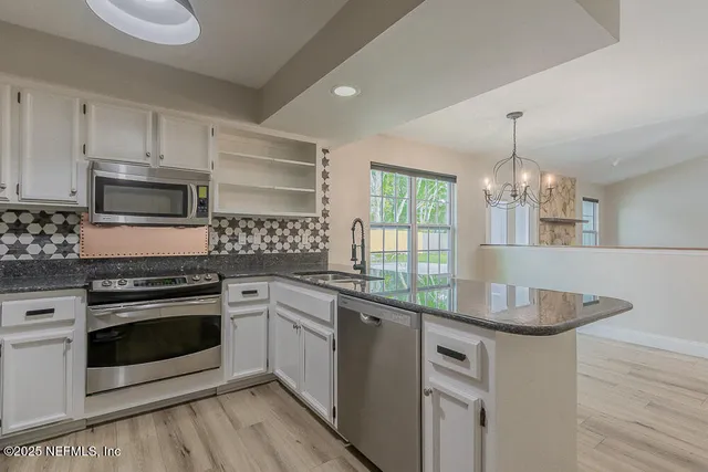 a kitchen with granite countertop stainless steel appliances a stove sink and microwave