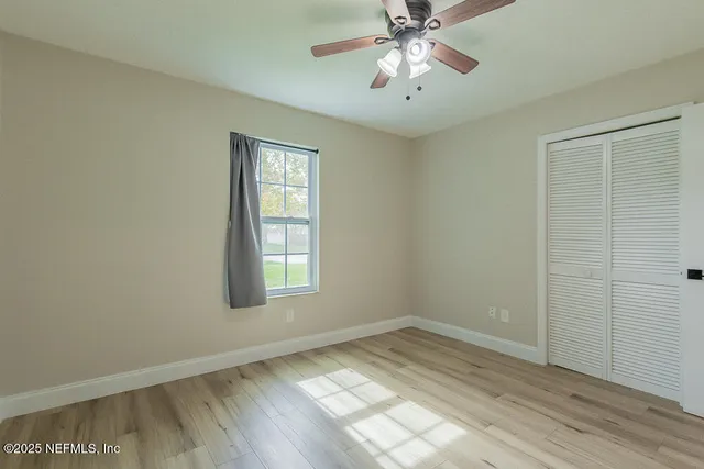 an empty room with a chandelier fan and windows