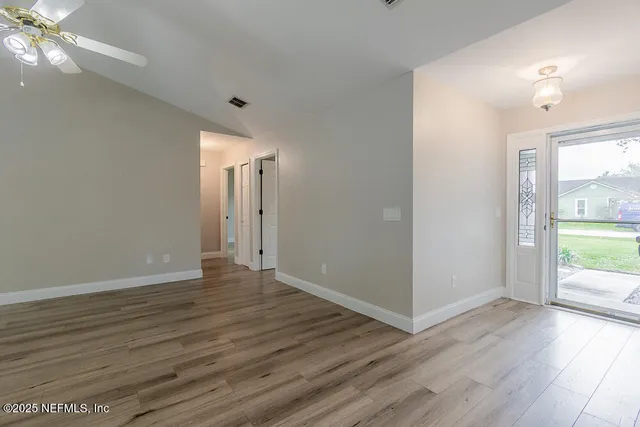 a view of an empty room with window and wooden floor