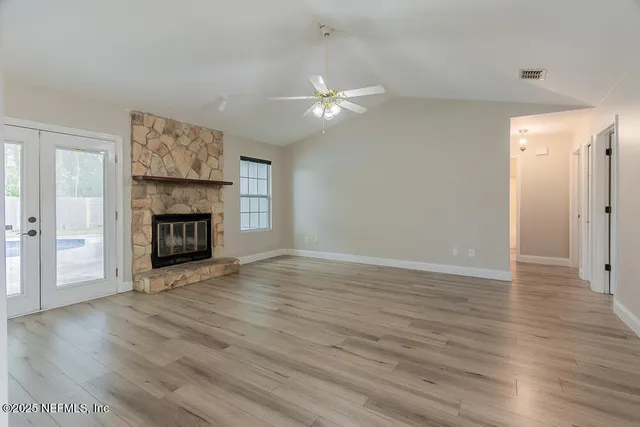 an empty room with wooden floor fireplace and windows