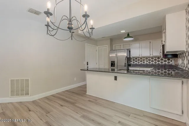 a view of a kitchen with stainless steel appliances granite countertop a sink a stove a microwave oven with wooden floor