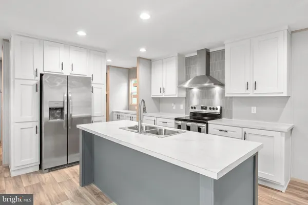 a kitchen with stainless steel appliances a sink a stove a refrigerator and cabinets