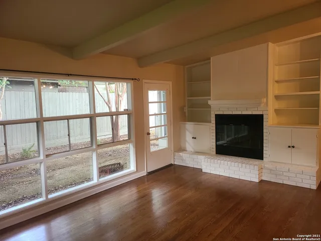 an empty room with wooden floor and fireplace