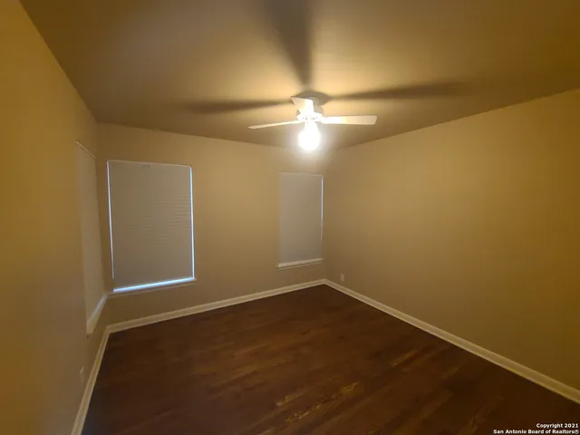an empty room with wooden floor and fan