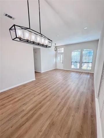 a view of an empty room with wooden floor and windows
