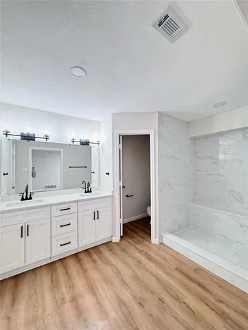 a large bathroom with a granite countertop double vanity sink a mirror and a bathtub