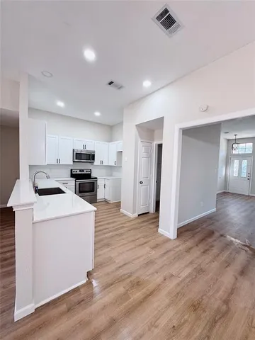 a kitchen with stainless steel appliances a refrigerator stove and wooden floor